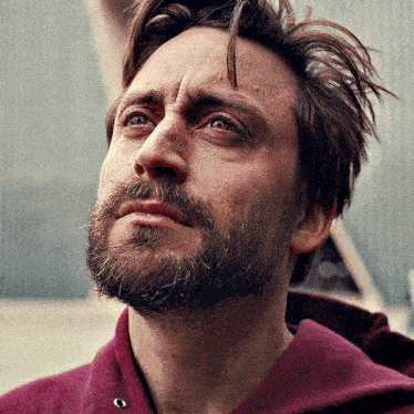 a man with a beard is wearing a purple sweater