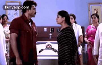 a man and a woman are standing next to each other in front of a dead baby in a hospital room .