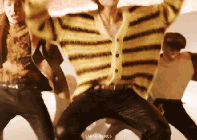 a man in a yellow and black striped sweater is dancing with other people