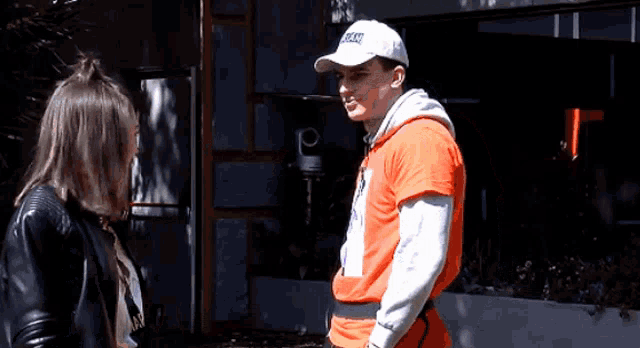 a man wearing an orange shirt and a white hat with the word run on it stands next to a woman