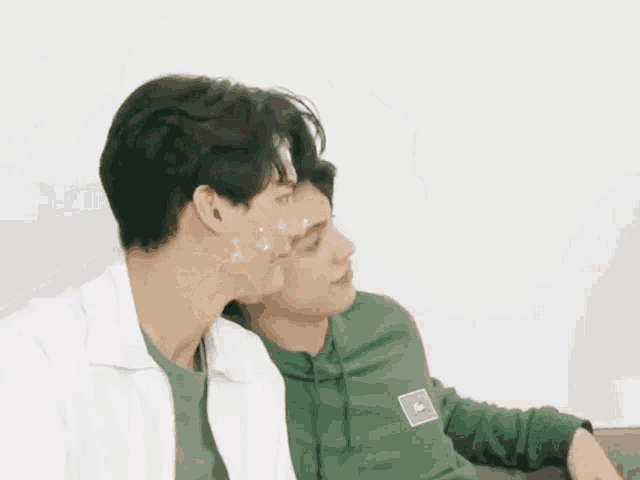 two men are sitting next to each other on a couch .