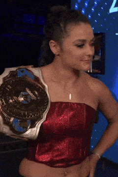 a woman wearing a red top is holding a championship belt