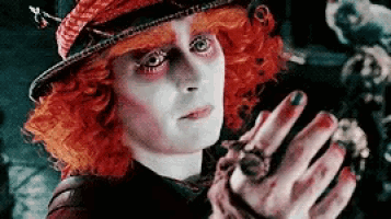 the mad hatter from alice in wonderland is holding a spider in his hand .