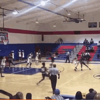 a basketball game is being played in a gym with a referee watching