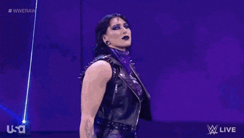 a female wrestler is holding a championship belt in her hand .
