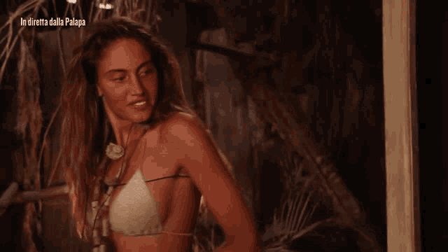 a woman in a bikini stands in front of a sign that says in diretta dalla palapa