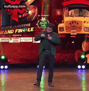 a man is dancing on a stage in front of a yellow truck .
