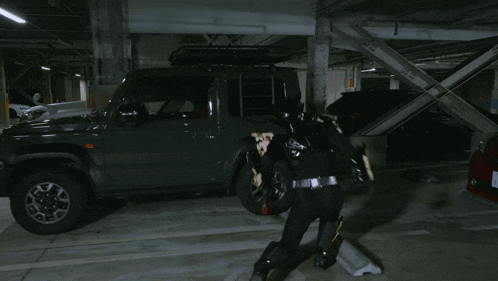 a person in a superhero costume is running in a parking garage next to a red car