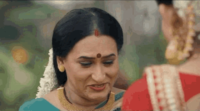 a woman with a red bindi on her forehead looks at another woman
