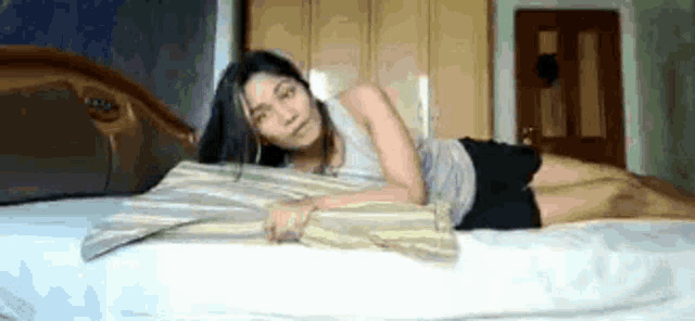 a woman is laying on her stomach on a bed with a pillow .