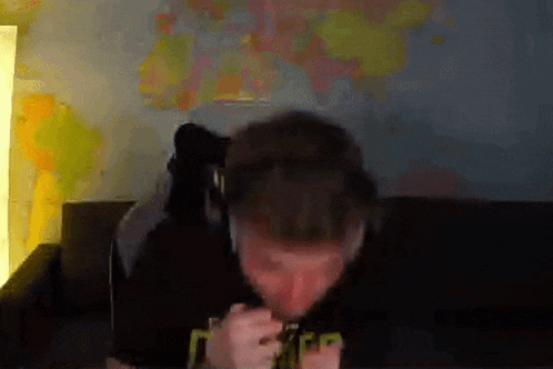 a man is sitting on a couch with headphones on and eating something .