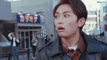 a man in a leather jacket stands in front of a sign that says " karaoke "