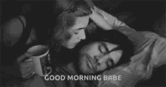 a woman is kissing a man on the forehead while he sleeps in bed .
