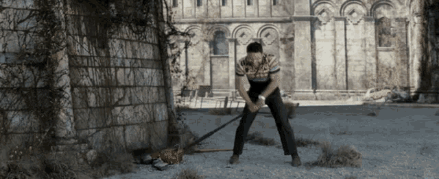 a man is standing in front of a brick wall with a broom in his hand