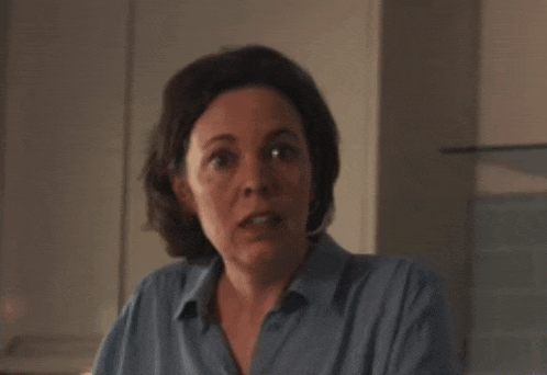 a woman in a blue shirt is looking at the camera and making a funny face .