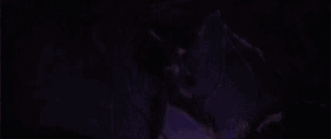 a person is standing in a dark room with a purple light coming from the ceiling .