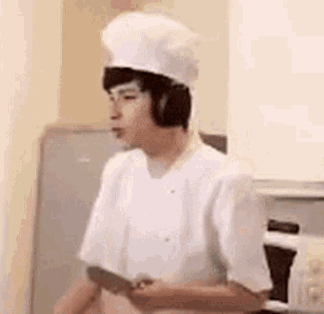 a man in a chef 's hat is standing in front of a refrigerator in a kitchen .