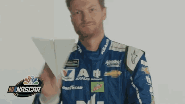 a man in a blue nascar uniform is holding a piece of paper
