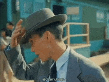 a man in a suit and hat is adjusting his hat .
