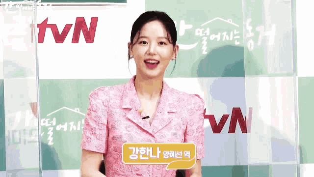 a woman in a pink dress stands in front of a tvn sign