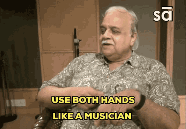a man is sitting in a chair with the words " use both hands like a musician " above him