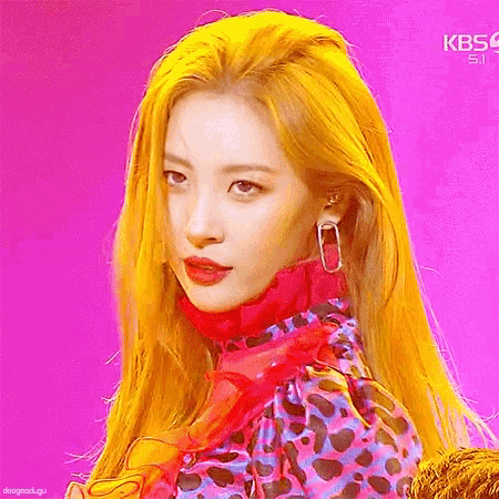 a woman with yellow hair and red lips is wearing a leopard print dress and earrings .