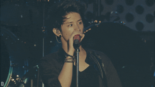 a man is singing into a microphone with the letter d behind him