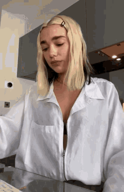 a woman with blonde hair is wearing a white shirt with a zipper on the front