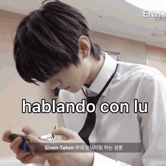 a man in a white shirt and tie is holding a cell phone with the words hablando con lu written below him