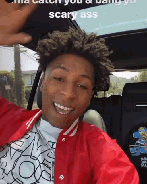 a young man in a red jacket is sitting in a car .