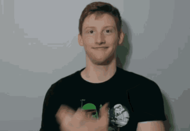 a man wearing a black shirt with a stormtrooper on it is making a funny face .