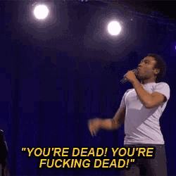 a man singing into a microphone with the words " you 're dead you 're fucking dead " on the bottom