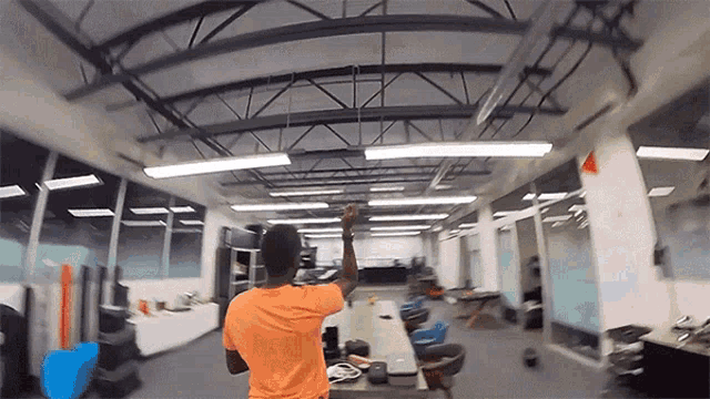 a man in an orange shirt stands in an office