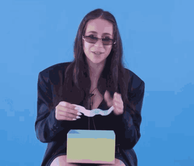 a woman wearing sunglasses is holding a piece of paper in her hand