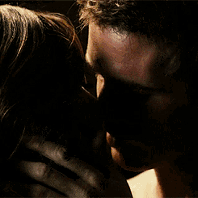 a man and a woman kissing in front of a sign that says ' a ' on it