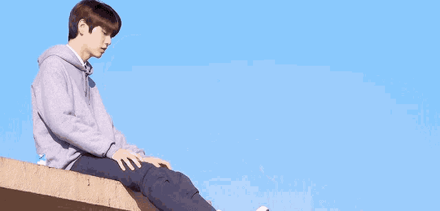 a young man is sitting on the edge of a building with his legs crossed