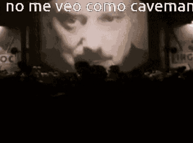 a large screen with a man 's face on it and the words no me veo como caveman above it