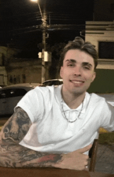 a man with tattoos on his arms is sitting at a table and smiling