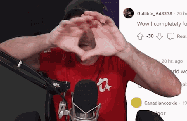 a man in a red shirt making a heart shape with his hands