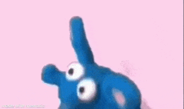 a blue stuffed animal is standing on a pink background .
