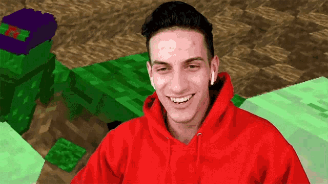 a man in a red hoodie is smiling in front of a minecraft scene