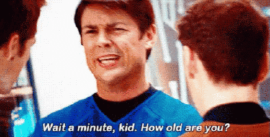 a man in a blue shirt is talking to another man while another man looks on .