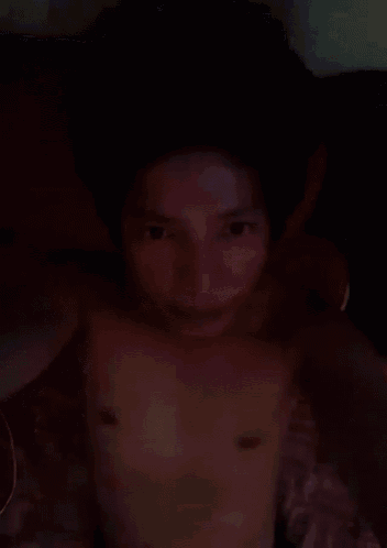 a man without a shirt is laying on a bed in the dark