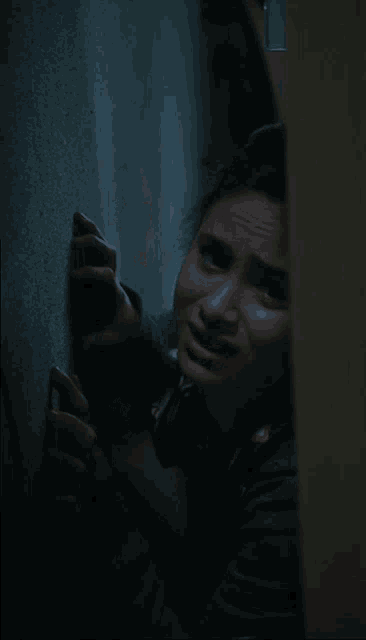 a woman is peeking out from behind a door and making a funny face