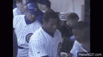 a group of baseball players are standing in a dugout talking to each other .