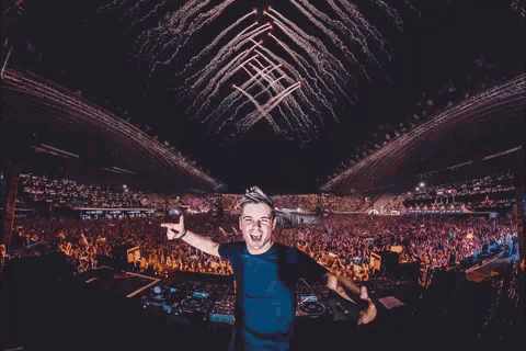 a dj is standing in front of a crowd with fireworks going off in the background