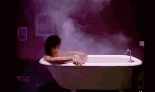 a woman is taking a bath in a bathtub in a dark room .