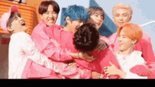 a group of young men in pink shirts are hugging each other and laughing .