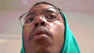 a close up of a man wearing glasses and a green scarf around his neck