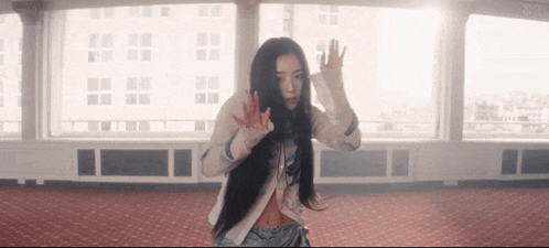 a woman with long hair is dancing in front of a window with the letters st on it